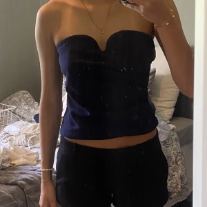 Mörkblå axelbandslös tubtopp - Säljer en stilren mörkblå axelbandslös tubtopp med snygg sweetheart-urringning. Toppen är croppad och har dragkedja i ryggen för enkel på- och avtagning. 