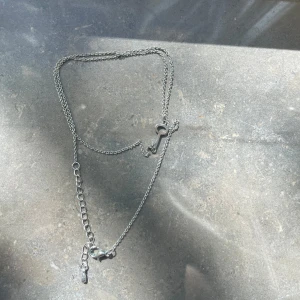 Silverfärgat halsband med nyckelberlock - Stilrent halsband i silverfärg med tunn kedja och en liten nyckel som berlock. Justerbar längd med förlängningskedja och lås.