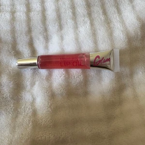 Glam of Sweden Lip Oil rosa - Fuktgivande lip oil från Glam of Sweden i en snygg rosa nyans. Kommer i en tub med silvrig kork och transparent kropp så du ser färgen. Perfekt för att ge läpparna glans och mjukhet. Enkel att ta med i väskan.