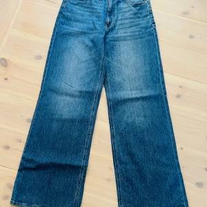 Wide jeans från Carin Wester, blå - Snygga blå jeans från Carin Wester i modellen Sasha. Byxorna har en rak och wide passform med hög midja och klassisk femficksdesign. Tillverkade i bomull med inslag av återvunnen bomull och lite elastan för extra komfort. Upplevs något stora. 
