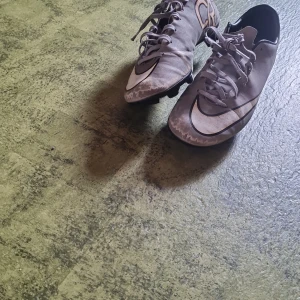 Nike Mercurial CR7 fotbollsskor grå - Säljer ett par grå Nike Mercurial CR7 fotbollsskor med svart och silverdetaljer. Skorna har snörning, låg profil och CR7-logga på hälen. Perfekta för dig som vill sticka ut på planen med stilrena och snabba skor.
