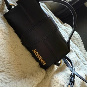 Jacquemus Le Bambino svart handväska - Säljer en Jacquemus Le Bambino handväska i svart skinn. Perfekt storlek för det viktigaste. Äkta. Använd en gång utanför hemmet.