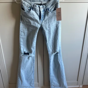 Ljusblå bootcut jeans med slitningar - Snygga ljusblå jeans från Nelly med bootcut  och slitna hål över knäna💖pris kan diskuteras 