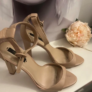 Beige klackade sandaler från Zara - Snygga beige sandaler från Zara Basic med öppen tå och bred rem över foten. Skorna har en stadig klack och justerbart spänne runt vristen. Perfekta för dig som gillar stilrena. Köpte för 850 säljer för 200kr 