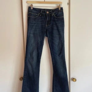 Mörkblå bootcut jeans från Mavi - Snygga mörkblå jeans från Mavi med bootcut passform. Klassisk femficksdesign, kontrastsömmar och detaljerade bakfickor. Jeansen är i stretchigt denim och har en medelhög midja. Perfekta för dig som gillar en tidlös jeansstil. Tyvärr en litet hål vid inre lår (bild visas) men det syns inte då det är såpass gömt mellan benen. Går att sy ihop såklart.