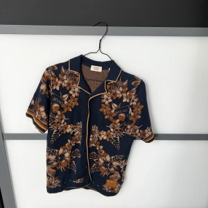 Scotch & Soda skjorta - Skjorta från Scotch and Soda. Blommiga mönster i guld med text.