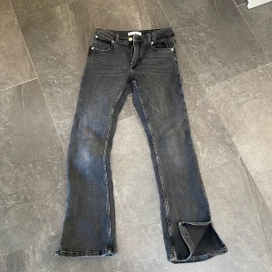 Svarta bootcut jeans från Zara - Snygga gråa jeans från Zara i bootcut-modell med stretch , klassisk femficksdesign och dragkedja. Jeansen har en något tvättad look och är tillverkade i mjukt denimtyg. Slits i nederkant. Perfekta för dig som gillar en avslappnad men trendig stil.