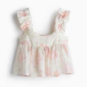 Blommig volangblus med knyt i ryggen - Supersöt blommig blus i ljusa rosa och vita toner med volangärmar och fyrkantig ringning. Toppen har en luftig, flowy passform och knyts i ryggen för en extra gullig detalj. Perfekt för vår och sommar när du vill känna dig extra söt!från hm helt slutsåld💕💕 