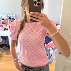 Rosa blommig blus från Vero Moda - Supersöt rosa blus från Vero Moda med blommigt spetsmönster och puffiga korta ärmar. 