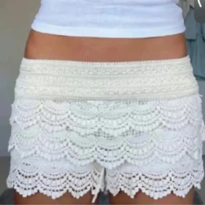 Vita virkade spets-shorts - Superfina vita shorts med virkade spetsdetaljer och vågiga kanter. De är högmidjade och har en romantisk, boho-inspirerad look som passar perfekt till sommaren. Materialet känns lätt och luftigt, vilket gör dem sköna att bära varma dagar. Helt oanvända