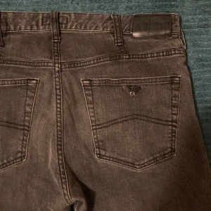 Gråa jeans från Armani - Snygga gråa jeans från Armani med klassisk femficksdesign och en diskret logga på bakfickan. Perfekta för en stilren look. Passar bra till både vardag och mer uppklädda tillfällen.