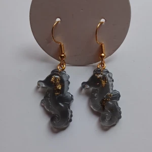 Örhängen med sjöhästar i glas - 2a utrensning! 3 olika par, säg till vilket par du vill ha vid köp. Unika örhängen med sjöhästar i genomskinligt glas med inslag av guld. De hänger från guldfärgade krokar och har en elegant och lekfull design.