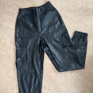 Svarta cargopants - Snygga cargopants i skinnmaterial från New Yorker. Byxorna har flera praktiska fickor och har en mjuk insida. Perfekt för en cool och avslappnad stil 🖤