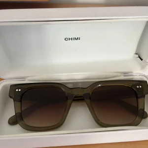 CHIMI 04 gröna - Snygga solglasögon från CHIMI med en fyrkantig form och transparent mörkgrön färg. Perfekta för att ge en cool touch till din stil. Kommer i ett elegant fodral. Sparsamt använda, bara att höra av sig vid eventuella frågor eller funderingar!😃