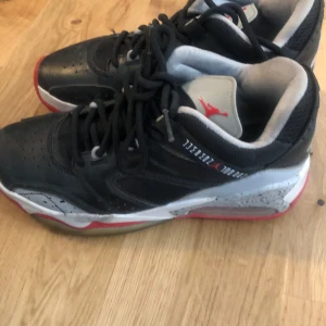Svarta Nike Air Jordans - Säljer ett par svarta Nike Air Jordans med röda och grå detaljer. I barnstorlek!