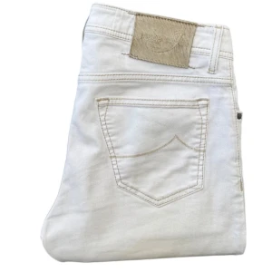 Vita jeansbyxor från Jacob Cohen - Snygga vita jeansbyxor från Jacob Cohen med klassisk femficksdesign och knappgylf. Byxorna har en stilren look med diskreta sömmar och en patch på baksidan. Perfekta för en stilren och fräsch outfit. Modell 688.