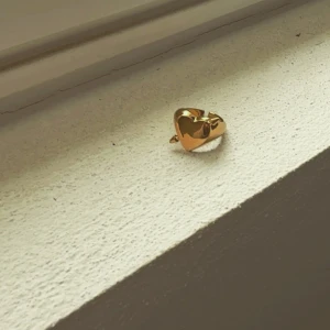 Guldfärgad arrow hjärtring - Säljer en stilren guldfärgad ring med ett stort hjärta som detalj. Perfekt för att ge en romantisk touch till din outfit. 💛 Den är helt ny och passar bra till allt💕💕den är också justerbar så passar till alla