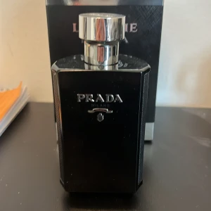 Prada L’homme Intense Eau de Parfum - Säljer en elegant och maskulin L'Homme Prada Intense Eau de Parfum. Flaskan är stilrent designad i svart med silverdetaljer och rymmer 100 ml. Perfekt för den som vill ha en sofistikerad doft med intensitet och djup. En lyxig parfym för den moderna mannen.