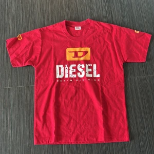 Röd t-shirt från Diesel - Säljer en cool röd t-shirt från Diesel med stort tryck på framsidan och mindre logga på baksidan. T-shirten har korta ärmar och rund halsringning. Perfekt för en avslappnad stil! Pris kan diskuteras.