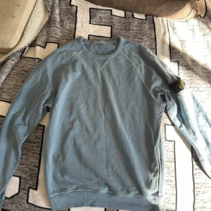 Ljusblå tröja från Stone Island - Säljer en stilren ljusblå tröja från Stone Island. Tröjan har långa ärmar och en klassisk rund halsringning. Storlek M. Fråga vid minsta fundering!