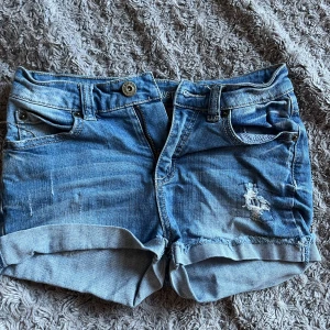 Blå  low waist jeansshorts från LA Industries - Säljer ett par snygga blå jeansshorts från LA Industries. De har en cool slitning på framsidan och uppvikta ben. Perfekta för en avslappnad stil. 🩳