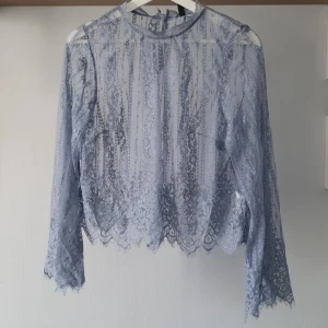 Ljusblå spetsblus från H&M Divided - Säljer en elegant ljusblå spetsblus från H&M Divided. Blusen har långa utsvängda ärmar och en fin knappdetalj i nacken! 💙 Sparsamt använd men någon enstaka tråd förekommer 
