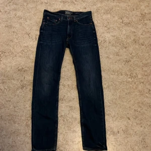Mörkblå jeans från Dressmann - Säljer ett par mörkblå jeans från Dressmann i regular fit. De har en klassisk femficksdesign och är tillverkade i ett slitstarkt denimtyg. Perfekta för en avslappnad stil.
