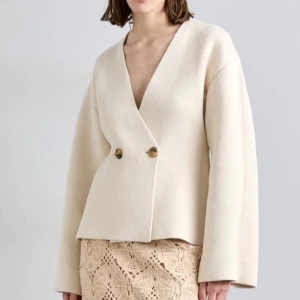 By Malene Birger cardigan (Helt ny)  - Elegant beige cardigan från By Malene Birger med en stilren omlott-design och två knappar framtill. Den har en v-ringad hals och långa ärmar. Den är helt ny med prislappen kvar. 