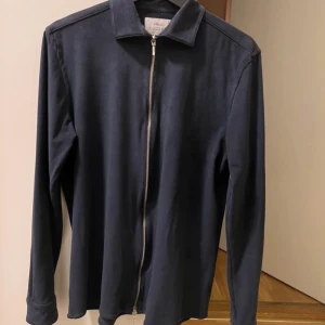 Mörkblå overshirt från Ciszere - Snygg mörkblå jacka från Ciszere med dragkedja framtill. Jackan har en klassisk krage och långa ärmar. Perfekt nu för våren. Gott skick utan defekter. Skriv vid minsta fråga eller fundering!