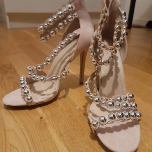 Rosa klackskor med pärldetaljer - Snygga rosa klackskor med öppen tå och dekorativa silverpärlor. Skorna har en hög klack och flera remmar som ger en elegant look. Perfekta för att sticka ut på festen! Skorna är i nyskick och knappt använda💞