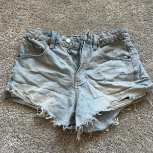 Ljusblå jeansshorts från Zara - Säljer ett par ljusblå jeansshorts från Zara med fransiga kanter och klassisk femficksdesign. Perfekta för sommardagar och ger en avslappnad look💕