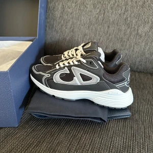 Svarta sneakers från Dior - Snygga svarta sneakers från Dior med vita detaljer och märkets logotyp på sidan. Skorna är oanvända, för mer info kom pm. 