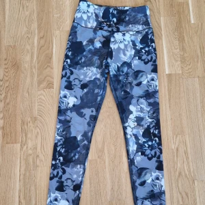 Blommiga leggings med hög midja - Gråblommiga leggings med hög midja köpta i New York. MYCKET mjuka, sköna och stretchiga. Lapparna bortklippta så minnet sviker på märket, men tror de kan ha inhandlats på Burlington, Union Square och passar S-M. Mått när de ligger platt 30-35 cm, kan stretchas ut ca 15 cm till. Längd ca 91 cm när de ligger platt. Någon tråd som kan behövas fixas, annars i gott skick.