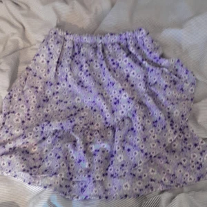 Lilla blommig kjol - Lila blommig kjol från Name it. Med små blommor på och med två volanger, och en stretch barr midja!!🪻