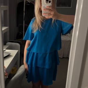Blå klänning med volanger - Säljer en härlig blå klänning med volanger. Den är i satin aktigt material, från Zara men säljs inte längre, jätte najs och luftig till sommaren 