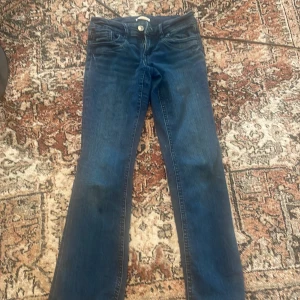 Blå bootcut jeans från Gina Tricot - Snygga blå jeans från Gina Tricot med klassisk bootcut-modell. Jeansen har fem fickor, normal passform och är tillverkade i ett mjukt denimtyg som sitter skönt. Perfekta för dig som gillar en tidlös look med lite utsvängda ben.