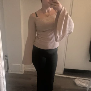 Beige offshoulder tröja med vida ärmar - Säljer en beige ribbad offshoulder tröja med supervida ärmar. Tröjan är figurnära och har en snygg, trendig passform som framhäver axlarna. Perfekt för dig som gillar unika detaljer och vill sticka ut lite extra.