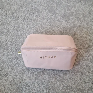 Rosa necessär från Hickap - Säljer en söt, ljusrosa necessär från Hickap med guldig dragkedja och vinrött innerfoder. Praktisk rektangulär form med extra innerficka för småsaker. Perfekt för smink eller andra småprylar när du är på språng. Helt oanvänd och limited edition från i vintras.