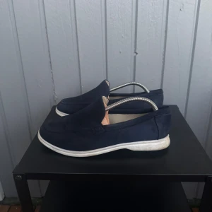 Mörkblå mockaloafers med vit sula - Snygga mörkblå loafers i mocka med vit platt sula.  Storlek - 41 men passar som 42 - då man ska gå ner en storlek i loafers. Mycket bra skick | skriv vid intresse :)