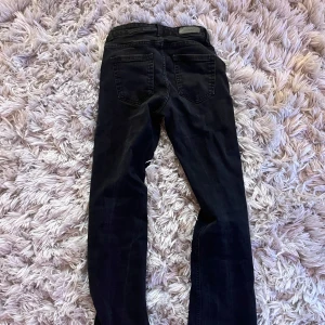 Svarta bootcut jeans från ONLY - Säljer ett par svarta bootcut jeans från ONLY med mellan midja. Snygg passform som sitter tight upptill och släpper ut vid benslut. Favvojeansen tills de blev för korta på mig och även därför jag säljer de då jag inte längre har användning för de. 