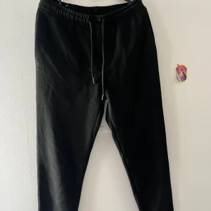 Svarta mjukisbyxor från Zara - Svarta mjukisbyxor från Zara med elastisk midja och snörning. Byxorna har raka ben, två bakfickor och är gjorda i ett mjukt material som känns skönt mot huden. Perfekta för en chill och avslappnad stil.