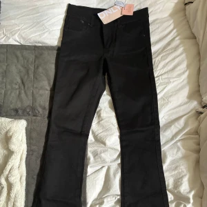 Svarta bootcut jeans från ONLY - Svarta jeans från ONLY med bootcut-snitt och klassisk femficksdesign. Jeansen har en stilren look och är tillverkade i ett stretchigt bomullsmaterial som sitter snyggt. Perfekta för dig som vill ha en tidlös och clean stil. Aldrig använda. 