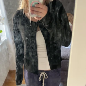 Svart kofta med lång ärm - En svart, tunn kofta från Gina Tricot med lång ärm och enkel design. Koftan har en liten öppning framtill vid halsen och är i ett mjukt, stretchigt material som känns skönt mot huden. Perfekt att slänga över ett linne eller t-shirt. Väldigt liten i storlek. 