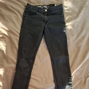 Mörkgrå skinny jeans med stretch - Snygga mörkgrå skinny jeans med klassisk femficksdesign och smal passform. Jeansen har normal midja och är tillverkade i stretchigt denimtyg för extra komfort. Perfekta för dig som gillar en tight och stilren look.