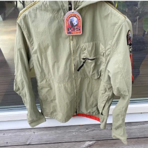 Parajumpers vindjacka i khaki grön - Snygg khakigrön vindjacka från Parajumpers. Jackan har en bröstficka med dragkedja och klassisk PJS-patch på axeln. Perfekt för dig som gillar streetstyle och funktionella plagg. Jackan är i xl men liten i storlek. Jag är 185 och den passar mig utmärkt. Pris kan diskuteras vid snabb affär