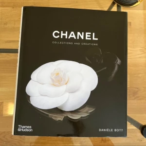 Chanel: Collections and Creations - En stilren bok om modeikonen Chanel, fylld med inspirerande bilder och berättelser om ikoniska kollektioner och design. Perfekt för dig som älskar mode, kreativitet och vill dyka in i Chanels värld av stil och elegans.