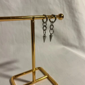 Silvriga örhängen med kedjor och spikes - Ett par coola silvriga örhängen med små kedjor och spetsiga spikes som hänger ner. Perfekta för dig som gillar en edgy och trendig stil. Örhängena är i metall och har en minimalistisk men ändå tuff design.