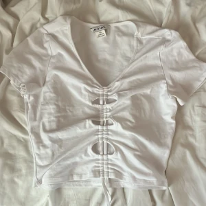 Vit croppad topp med snörning Monki - Säljer en vit croppad topp från Monki i bomull med korta ärmar och v-ringning. Typ aldrig använd, så väldigt bra skick!❤️