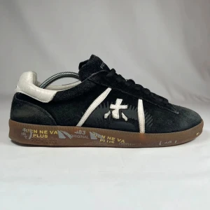 Svarta sneakers från Premiata  - Stilrena svarta sneakers från Premiata i mjuk mocka med vita detaljer och logga på sidan. Skorna har bruna gummisulor med tryck och svarta snören. Skriv för mått och vid frågor och funderingar!