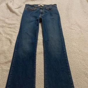 Levi's blå bootcut jeans - Klassiska blå lowwaist jeans från Levi's med bootcut passform. Jeansen har fem fickor, snygga kontrastsömmar och är tillverkade i slitstarkt denim. Perfekta för dig som gillar en tidlös och avslappnad stil. Kommer inte till användning då de ej passar 